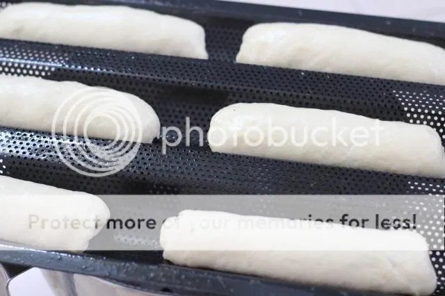 9 ổ bánh mì đã được tạo hình và xếp gọn gàng trên khay nướng, sẵn sàng cho công đoạn ủ cuối.