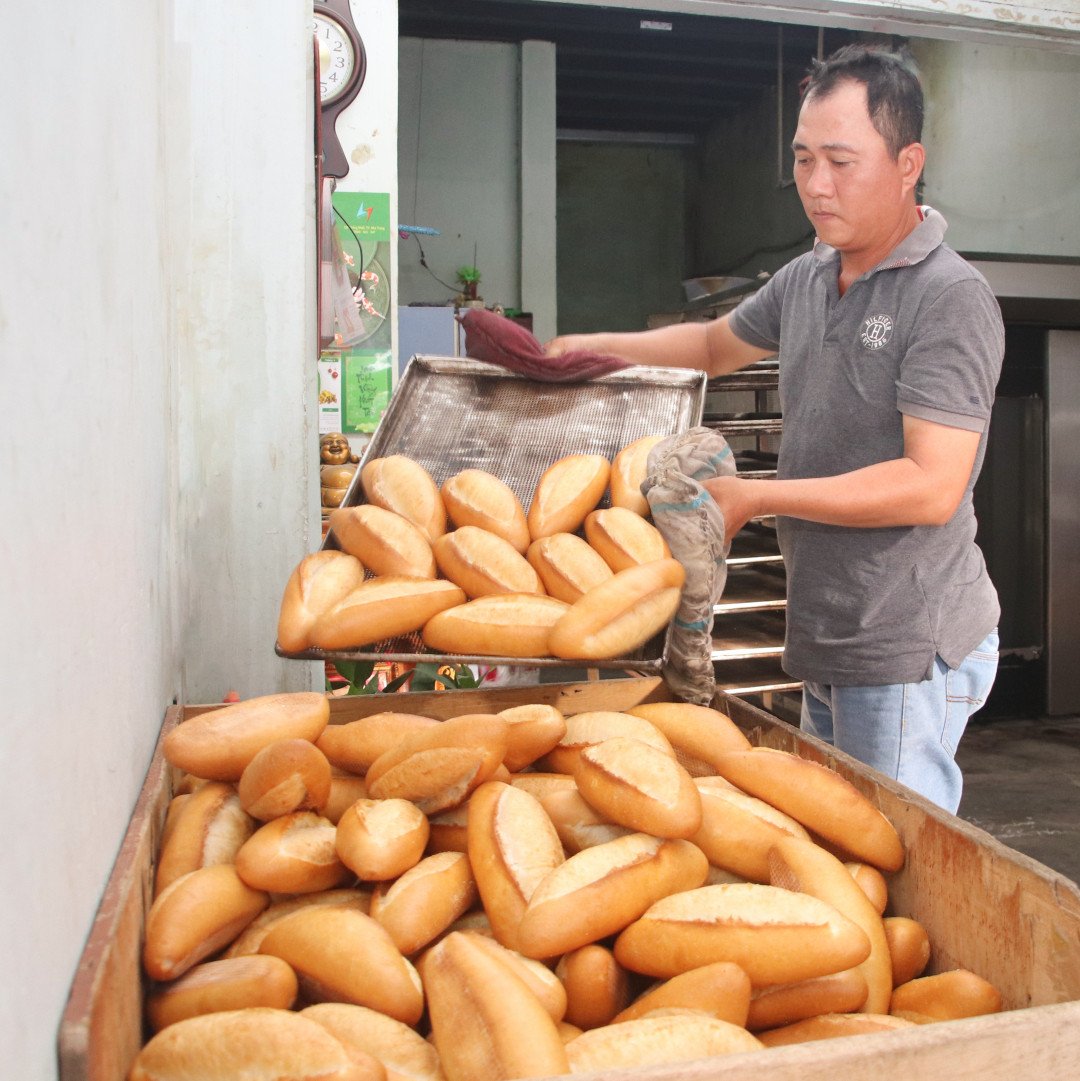 Anh Trần Văn Phúc đang trút những mẻ bánh mì Nha Trang nóng hổi, thơm lừng vừa ra khỏi lò