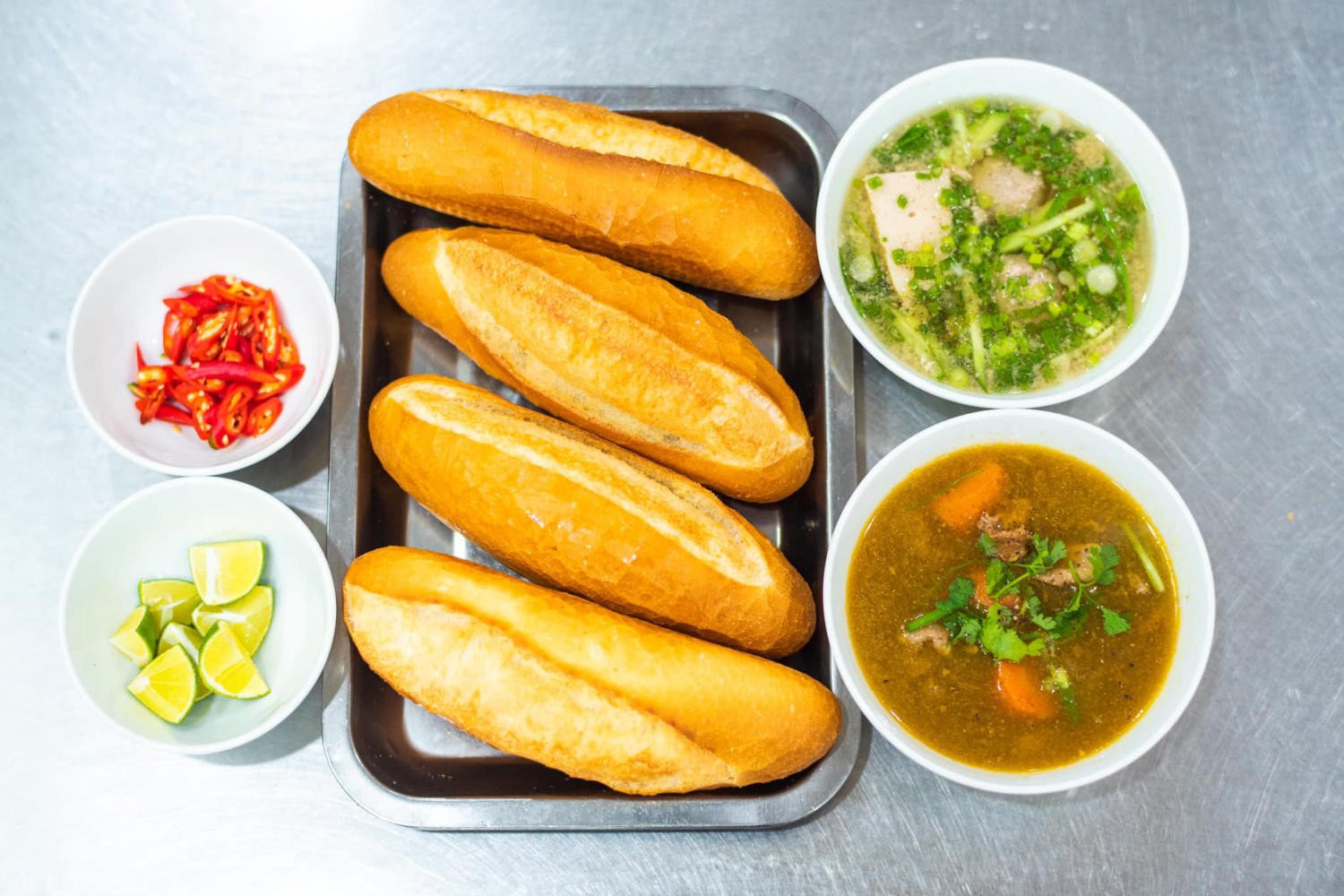 Bàn ăn tại chỗ với bánh mì và các loại đồ uống tại Bánh mì Lệ