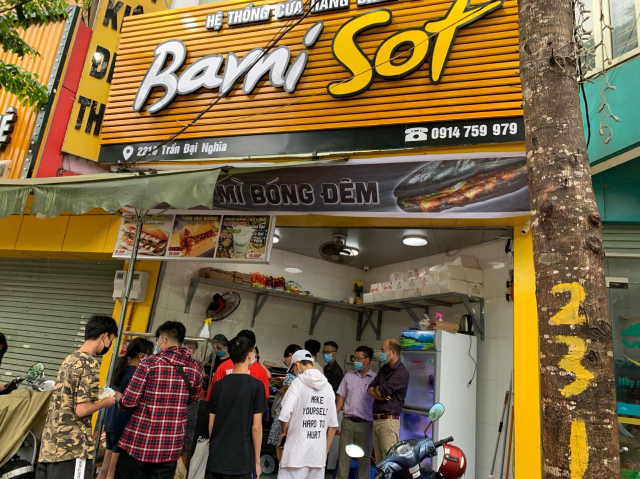 Bánh mì bami sot đen cầm trên tay với lớp vỏ giòn rụm và màu sắc hấp dẫn