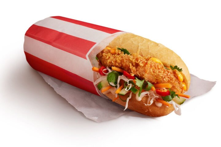 Bánh mì Zinger KFC với gà rán, dưa chuột, rau thơm trên đĩa