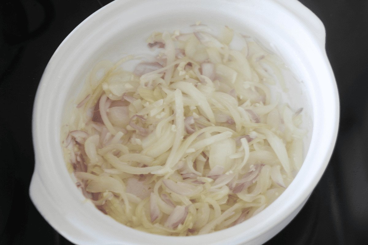 Các loại hành và tỏi đang được xào trên bếp để tạo hương thơm cho món bánh mì cá hộp.