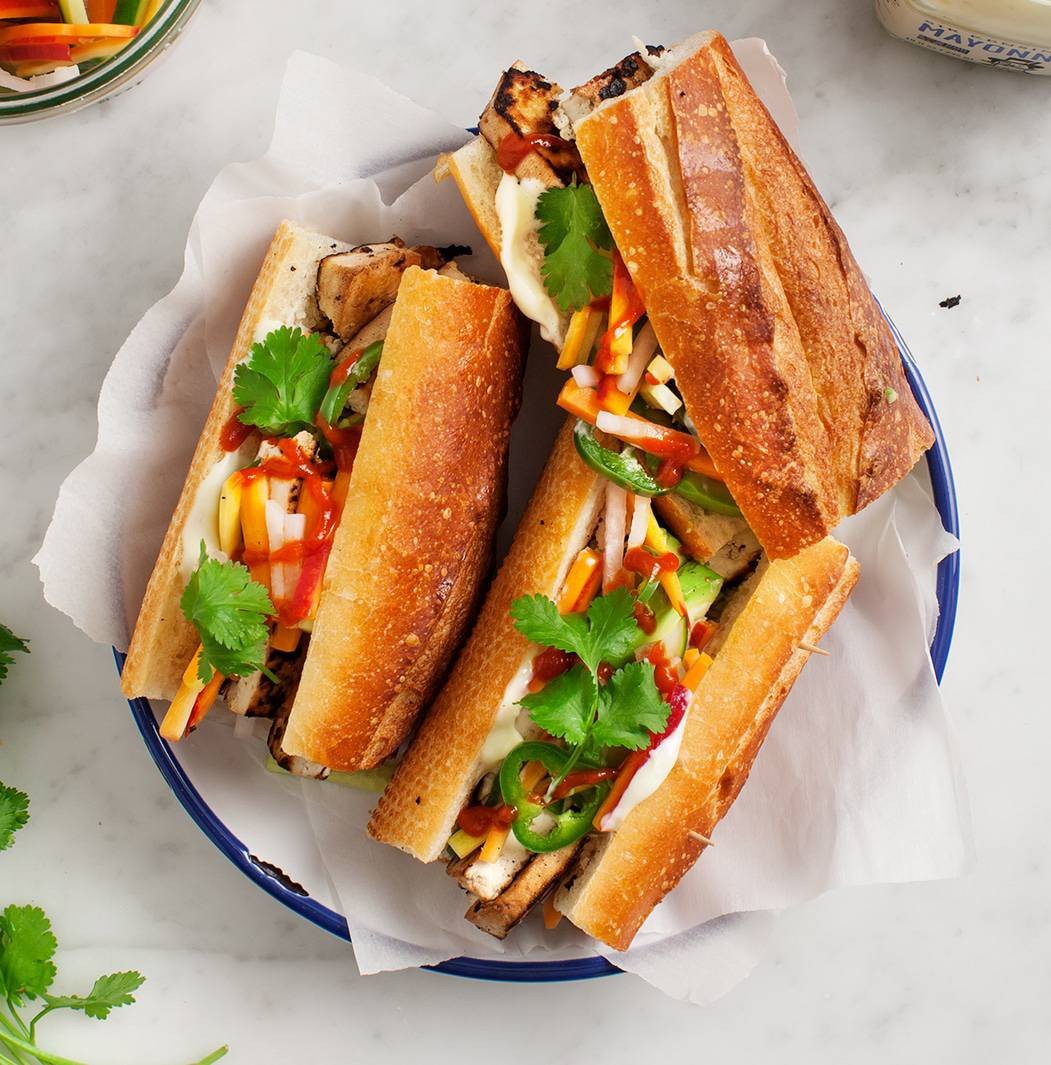 Cận cảnh chiếc bánh mì chay nhân đậu phụ vàng ruộm, rau thơm và sốt