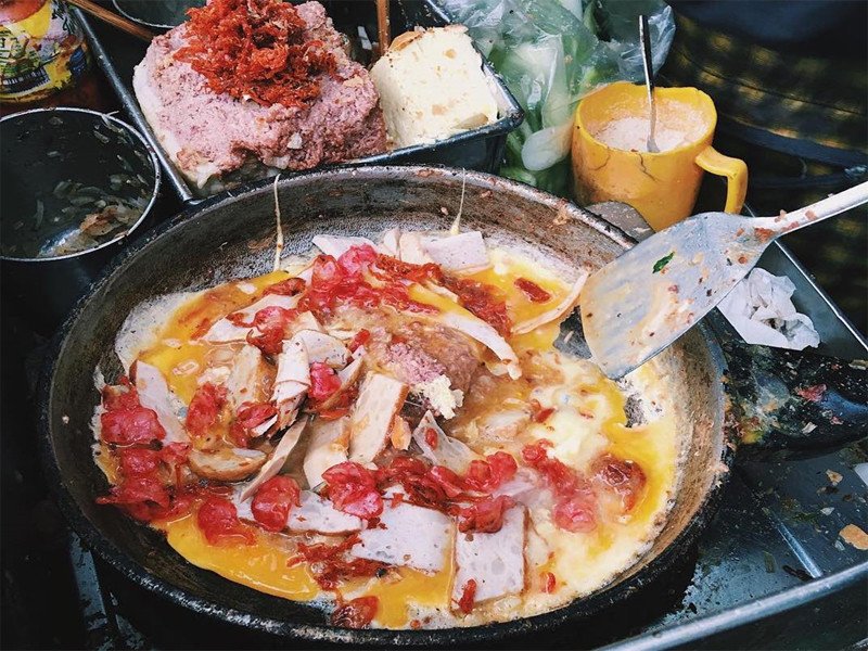 Chảo nhân bánh mì dân tổ đang được xào nóng hổi, hỗn hợp thịt chả và trứng béo ngậy