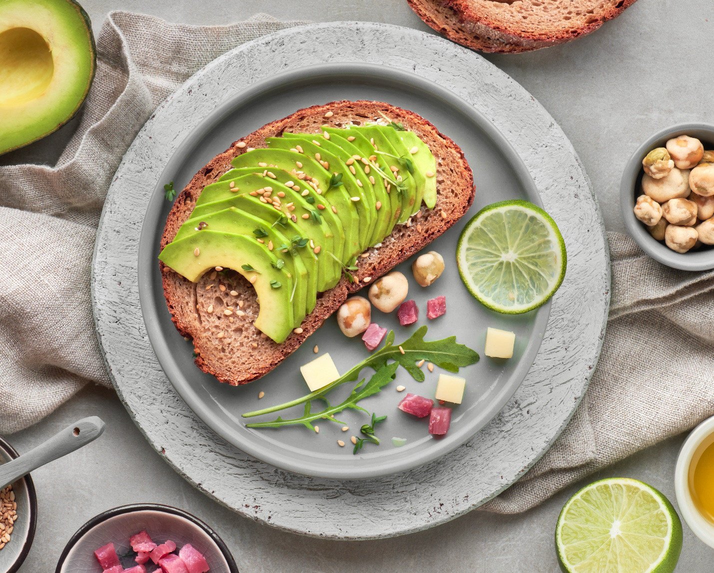 Đĩa bánh mì hạt nảy mầm nguyên ổ cắt lát cùng trái cây tươi và hạt, bữa ăn lành mạnh.