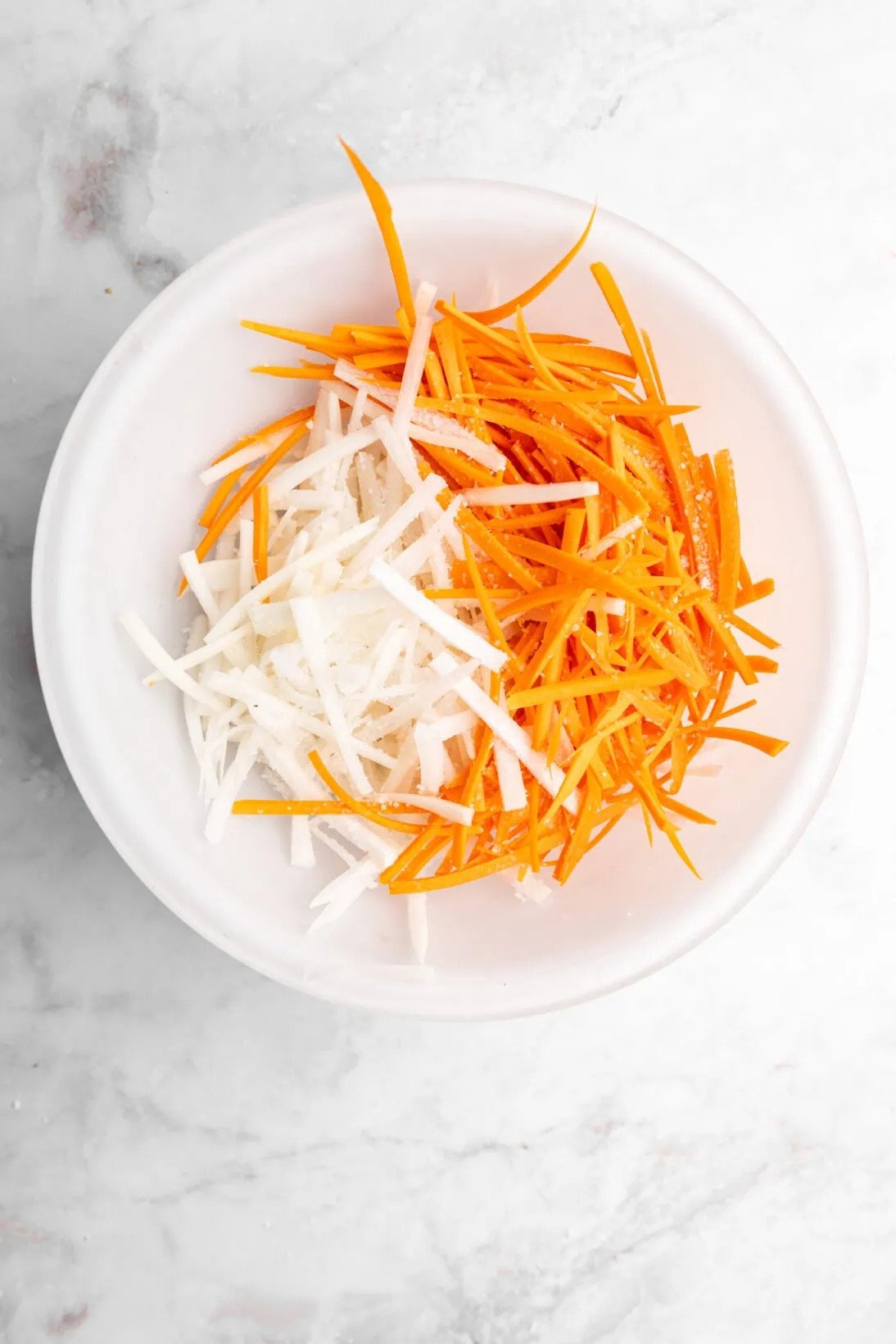 diakon and carrots being salted