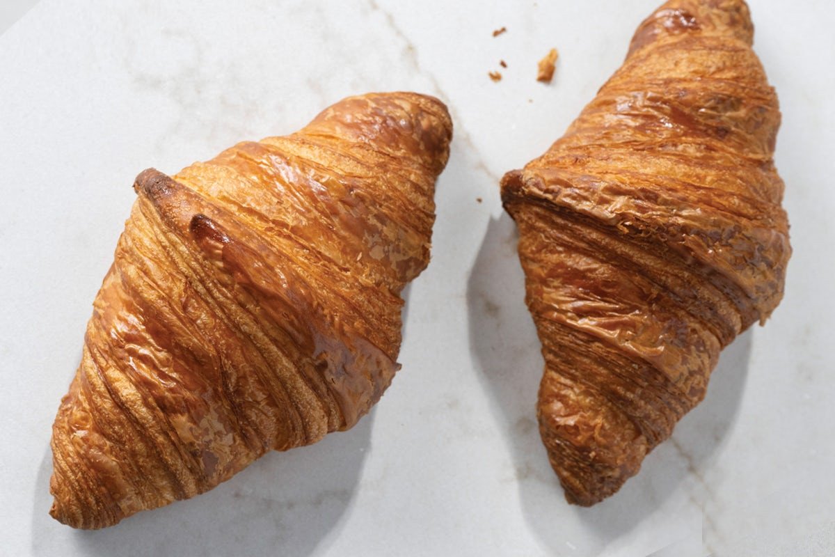 Hai chiếc Croissant vàng ươm trên khay gỗ