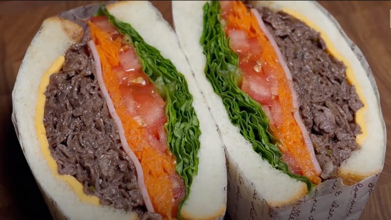 Hình ảnh người đang thưởng thức bánh mì sandwich kẹp thịt