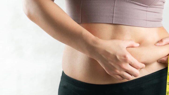 Hình ảnh người phụ nữ đang ôm vòng eo và biểu cảm lo lắng về eo bánh mì của mình