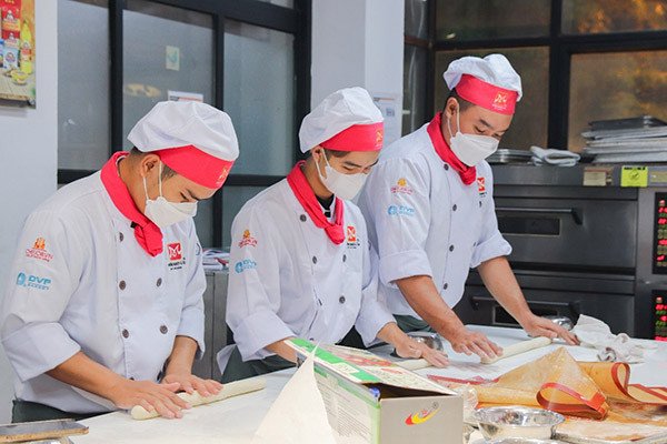 Học viên đang tạo hình bánh mì trong một buổi thực hành khóa học bánh mì