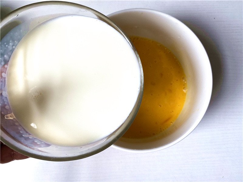 Hỗn hợp trứng và sữa tươi đang được khuấy đều để chuẩn bị cho món bánh mì nướng trứng sữa