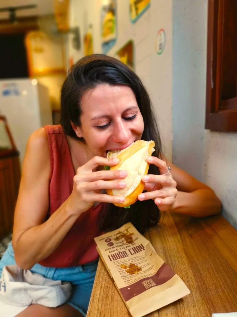 Katharina đang cắn một miếng bánh mì xanh tại Thành phố Hồ Chí Minh, thưởng thức hương vị thuần chay hấp dẫn.