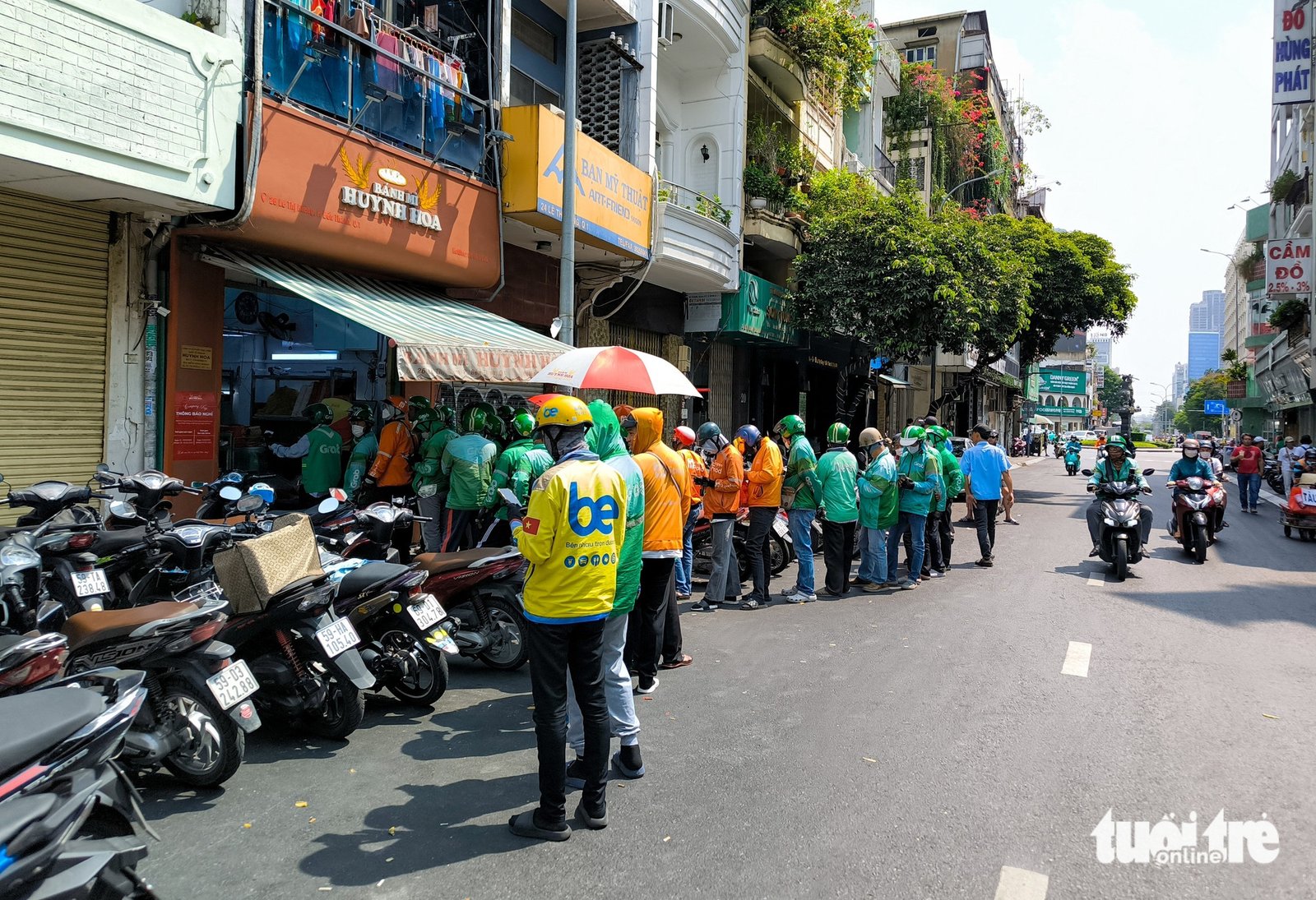 Khách hàng và xe máy chiếm gần nửa lòng đường khi chờ mua bánh mì Huỳnh Hoa TPHCM.