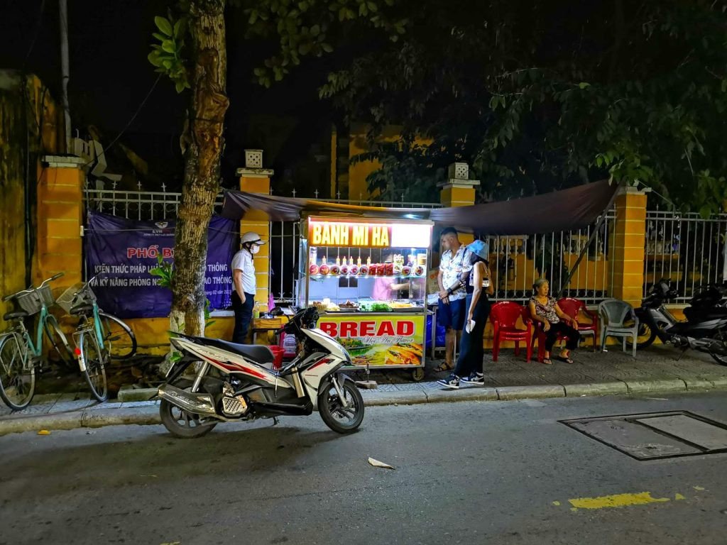 Khách hàng xếp hàng tại xe đẩy Bánh mì Hà Hội An, một điểm ăn uống đường phố được yêu thích.