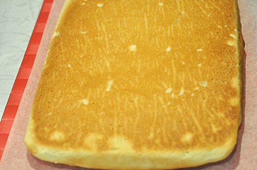 Lật ngược tấm bánh mì lên giấy nến để chuẩn bị trét nhân và cuộn thành bánh mì cuộn trứng.