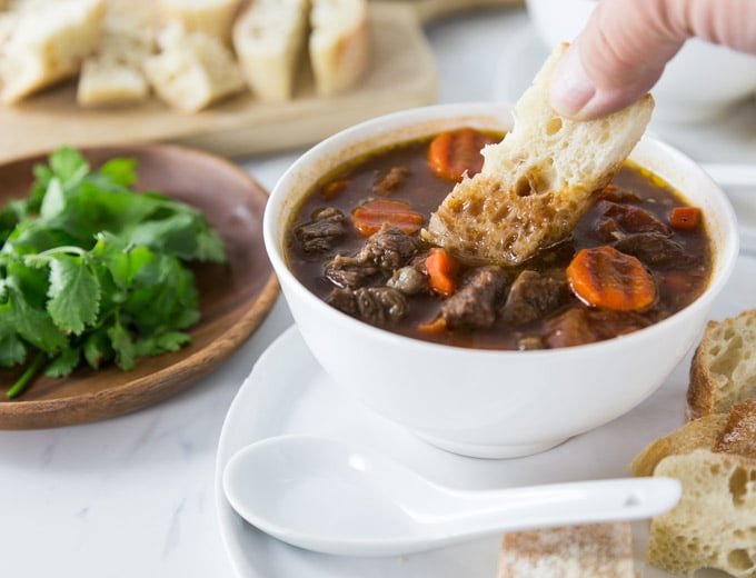 Miếng bánh mì được chấm vào nước sốt vang đậm đà, mô tả cách thưởng thức bánh mì sốt vang.