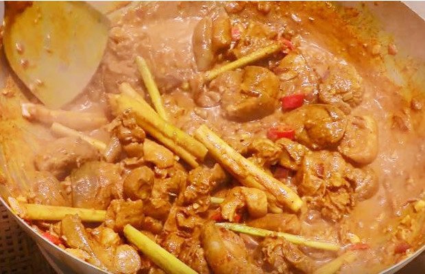 Món dê xào lăn bánh mì đang được nấu chín trong chảo với nước cốt dừa và các loại gia vị.