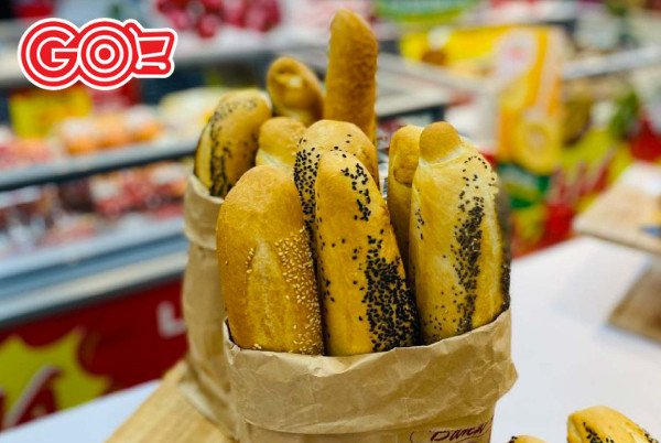 Một chiếc bánh mì thơm ngon đang được cắt, với nhân thịt và rau