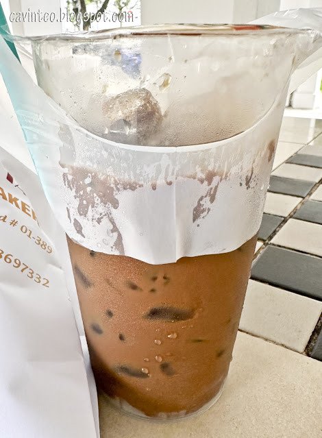 Một cốc cà phê sữa đá Việt Nam sánh mịn, đặt cạnh chiếc bánh mì