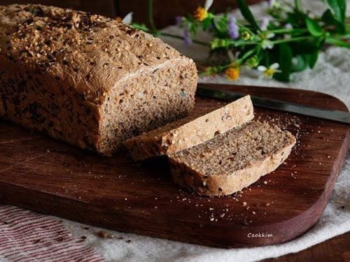 Một ổ bánh mì ngũ cốc nguyên hạt cắt lát, thể hiện cấu trúc chắc đặc và màu sắc tự nhiên, giàu chất xơ và dinh dưỡng.