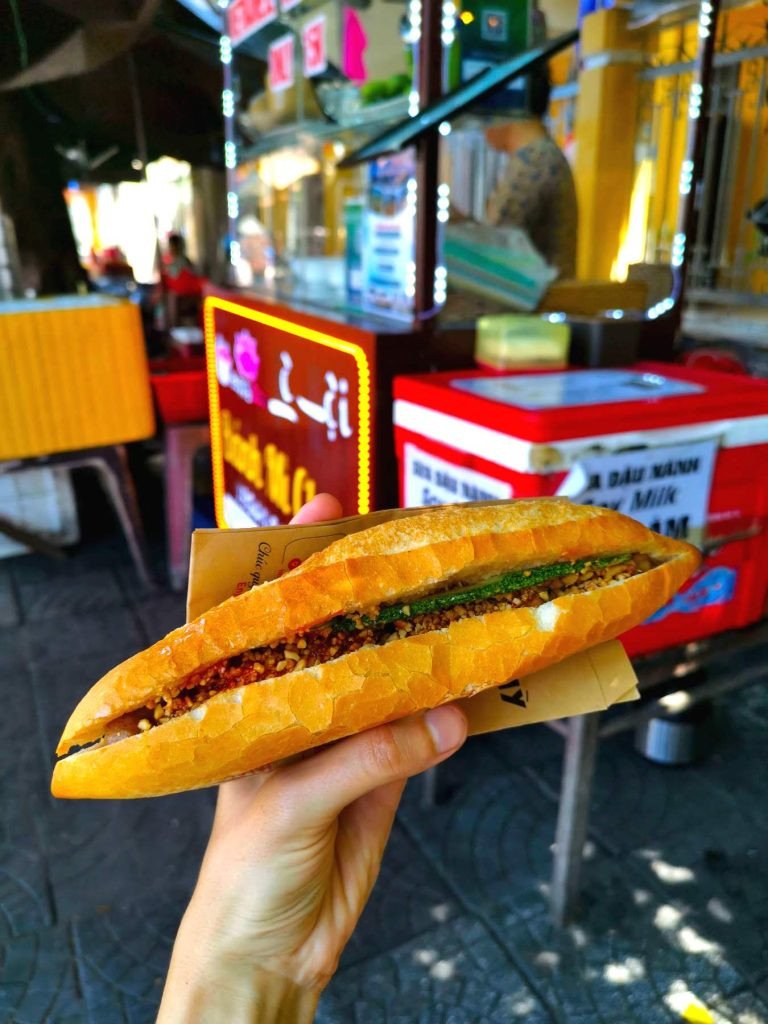 Một phụ nữ đang cắn một miếng bánh mì thuần chay thơm ngon tại Hội An.