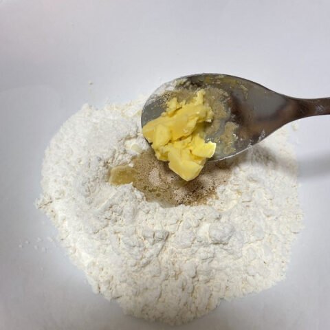 Người đang trộn bột khô trong tô lớn, chuẩn bị làm bánh mì mini bằng nồi chiên không dầu.