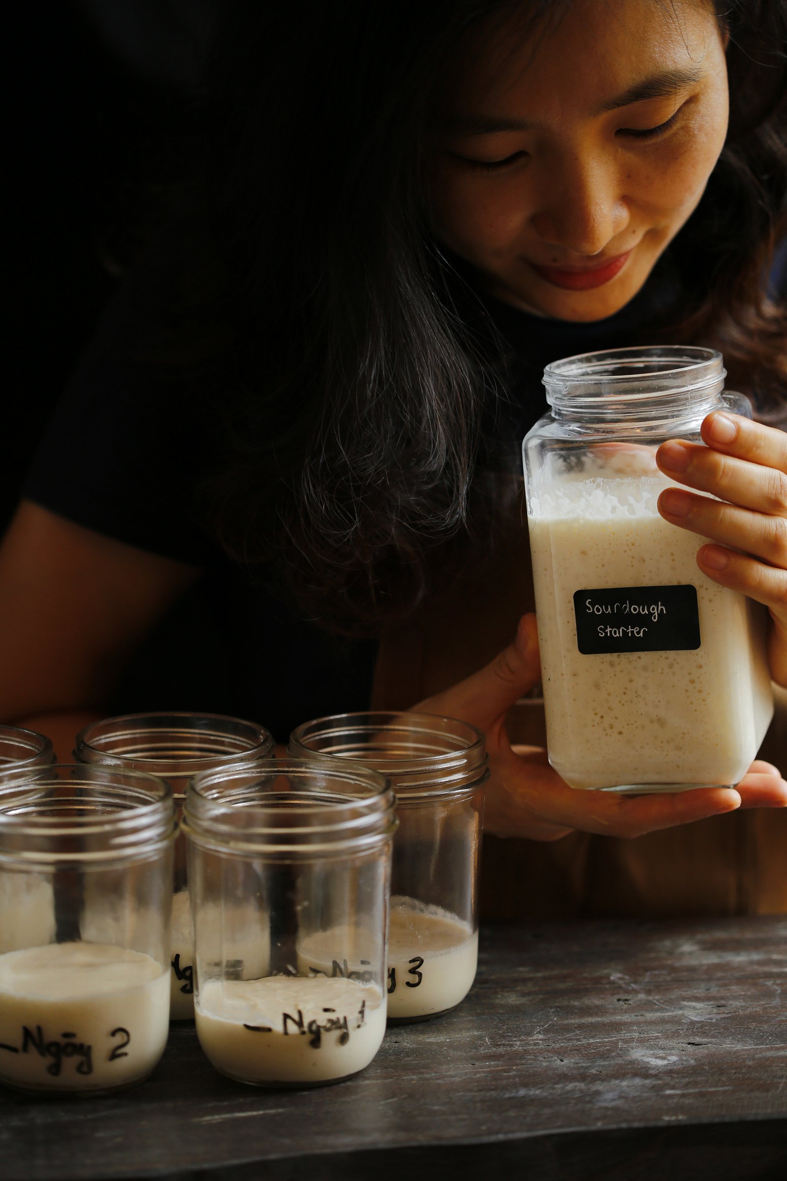 Người phụ nữ tươi cười bên những ổ bánh mì sourdough của mình