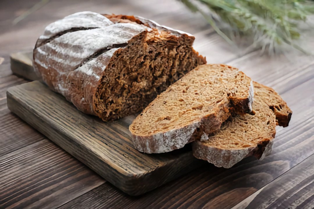 Những lát bánh mì lúa mạch đen đặc trưng trên thớt, thường là loại bánh mì chay