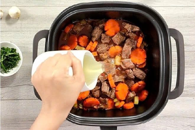 Nồi sốt vang bò đang sôi liu riu trên bếp, tỏa hương thơm ngào ngạt
