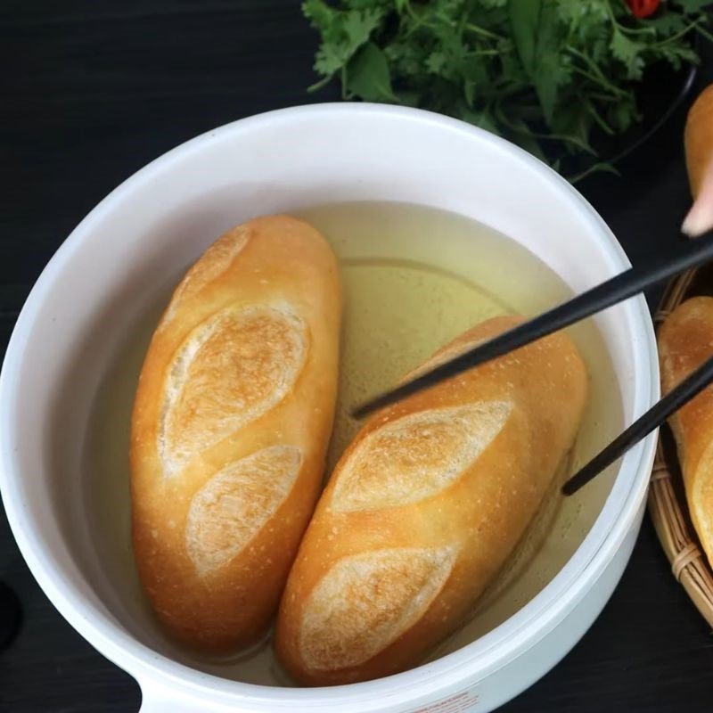 Nướng bánh mì trên chảo nóng để có lớp vỏ giòn rụm, sẵn sàng cho món bánh mì rau Hải Phòng