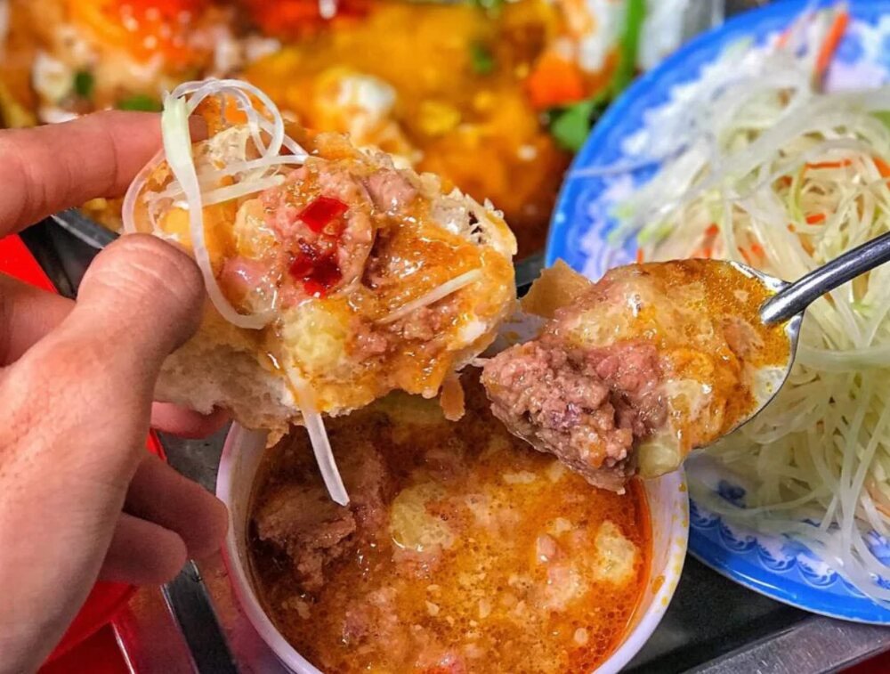 Ổ bánh mì chấm được xé nhỏ, chấm vào nước sốt và thưởng thức cùng rau sống
