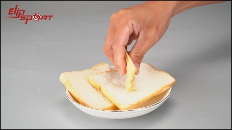 Phết bơ lên bánh mì, minh họa việc cần hạn chế bơ và phô mai khi ăn bánh mì bơ đậu phộng để kiểm soát lượng calo