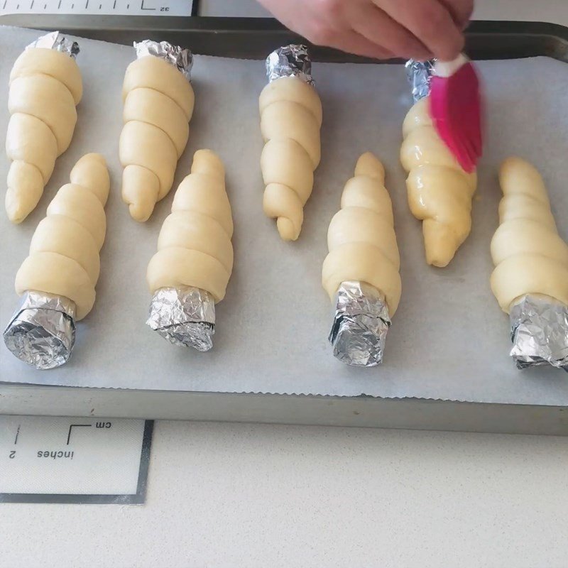 Phết lòng đỏ trứng lên vỏ bánh mì ốc quế trước khi nướng