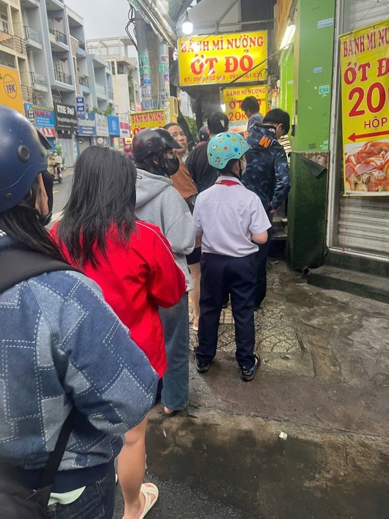 Quầy bánh mì nướng ớt Đỏ Tân Phú tấp nập khách mua hàng, với bánh mì đang được nướng trên than hồng