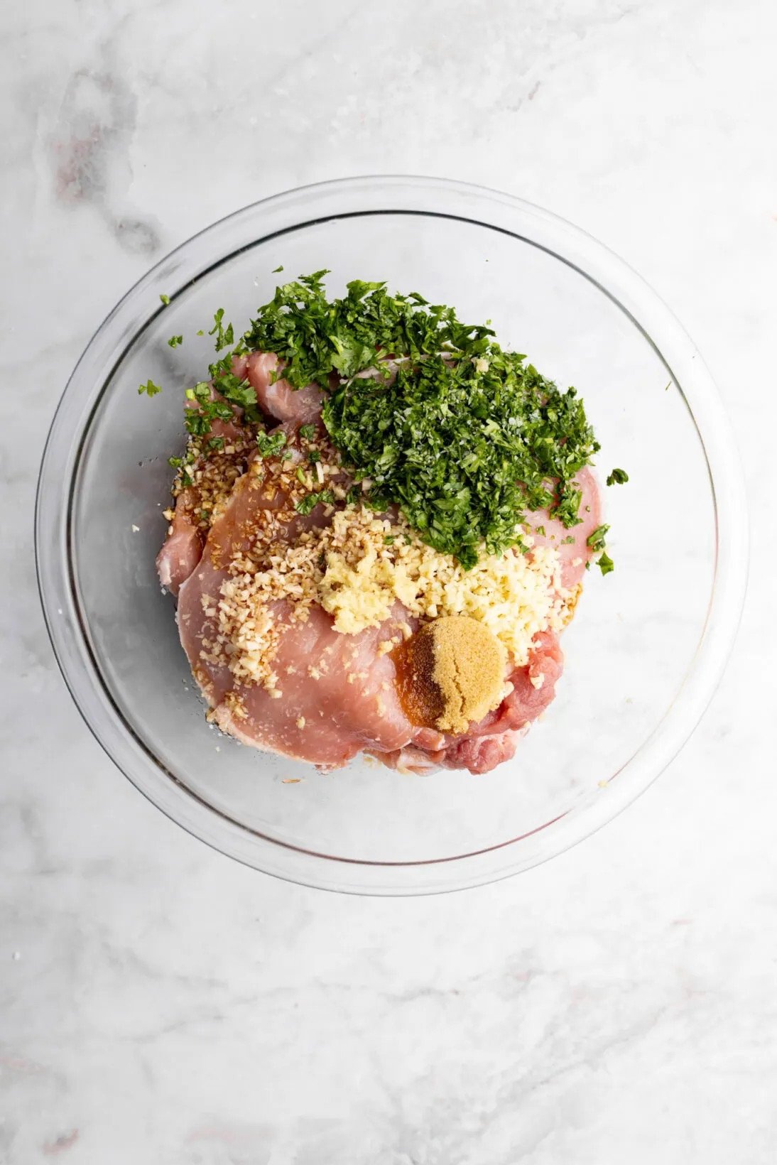 the prepped pork in a bowl with garlic, lemongrass, brown sugar, soy sauce, fish sauce, cilantro, and oil