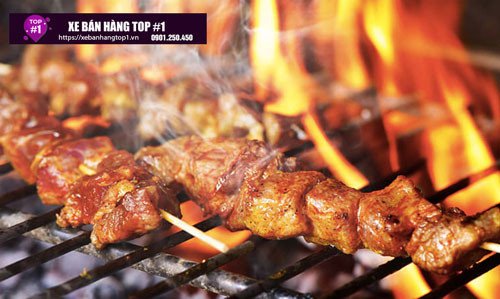 Thịt bò đang được nướng trên bếp than hồng, tạo hương thơm đặc trưng cho món bánh mì thịt bò