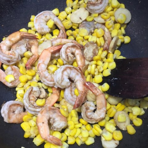 Tôm tươi đang được xào nhanh với tỏi phi thơm trong chảo lớn để chế biến tôm sốt phô mai