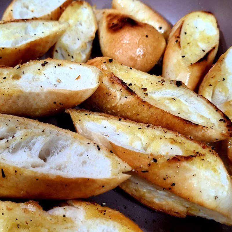 Trở đều bánh mì trên chảo để bơ tỏi thấm đều và vàng giòn