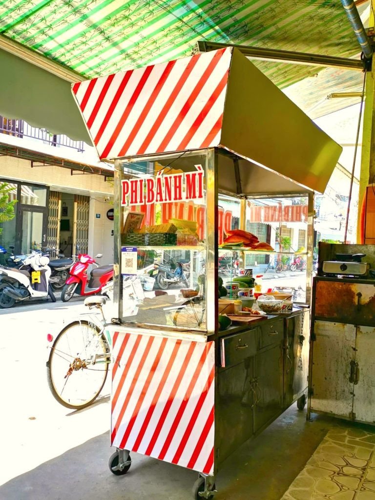 Xe đẩy thức ăn đường phố sọc đỏ trắng của Phi Bánh Mì Hội An.