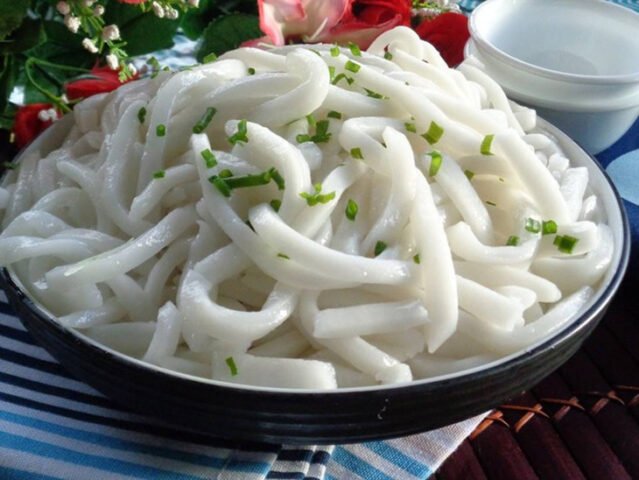 Bàn tay đang khéo léo cắt những miếng bột đã cán mỏng thành sợi bánh canh bột xắt đều tăm tắp