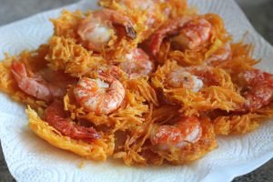 Bánh tôm đang được chiên vàng giòn trong chảo