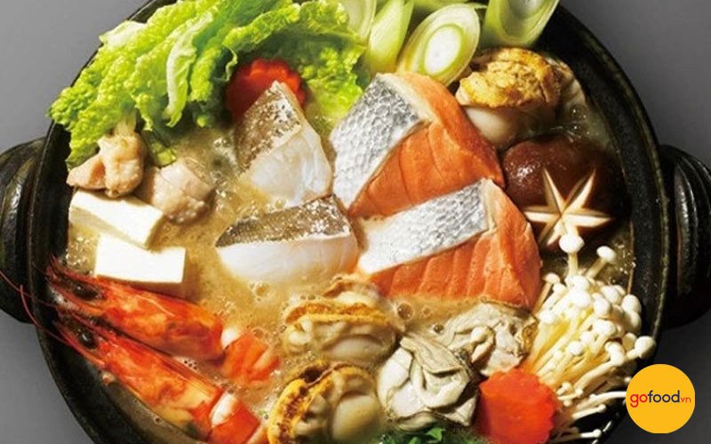 Bát lẩu cá hồi chua cay với miếng cá hồi béo ngậy và rau tươi