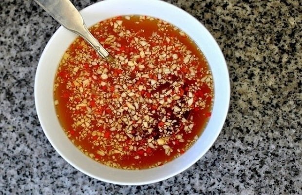Bát nước chấm chua ngọt với ớt và tỏi băm kèm dưa góp cho món bánh tôm chiên