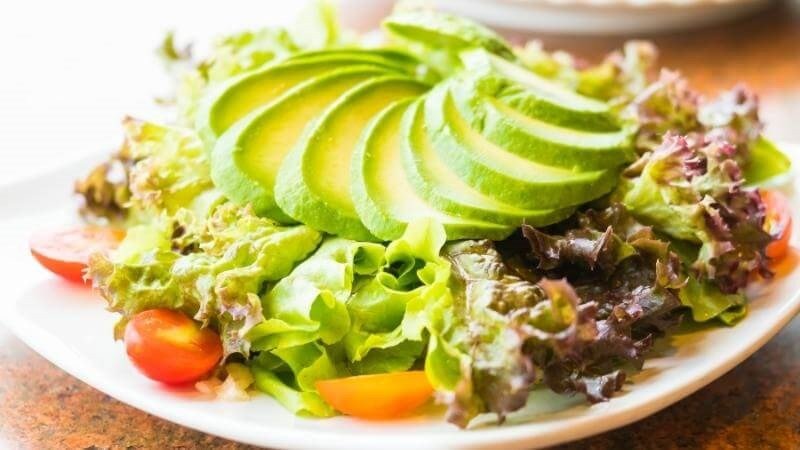 Bơ sáp cắt lát mỏng được sắp xếp trên đĩa salad rau tươi, cách bổ sung dinh dưỡng