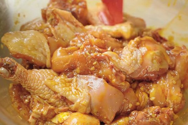 Các miếng thịt gà đang được ướp với gia vị cà ri, hành, tỏi, gừng để món gà cà ri thấm đều