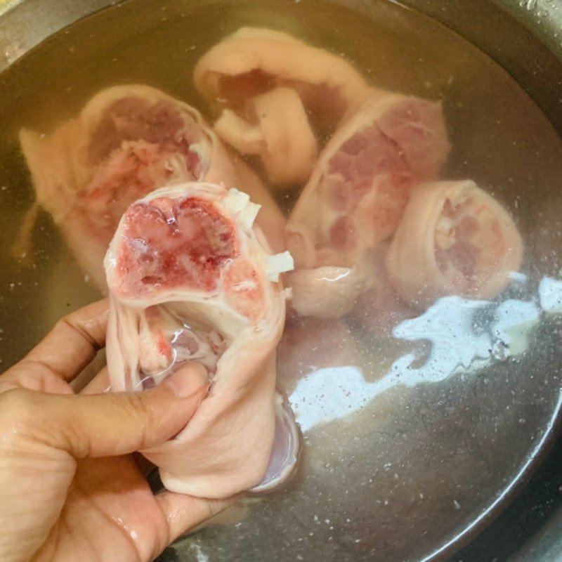 Chân giò heo đang được luộc sơ với gừng và muối để khử mùi