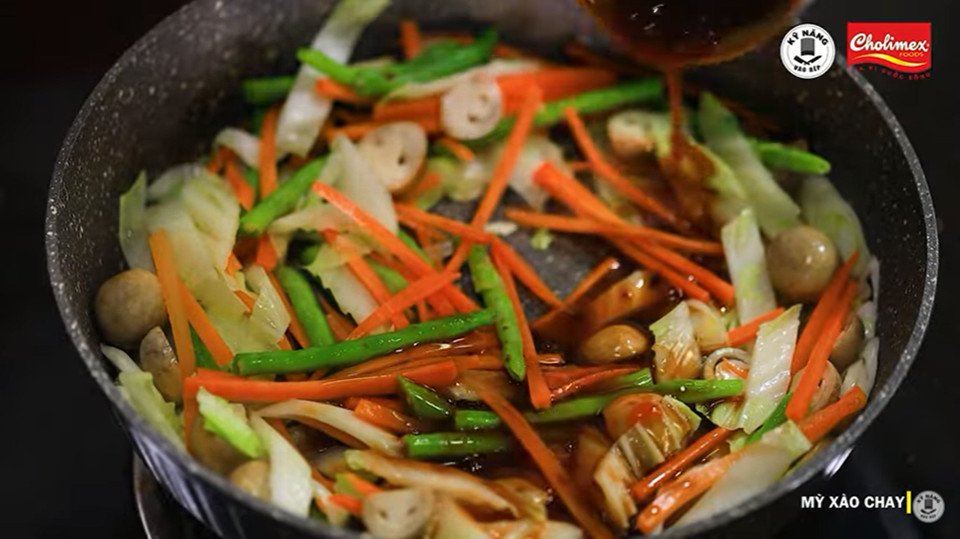 Chảo mì xào chay đang được trộn đều cùng rau củ và sốt