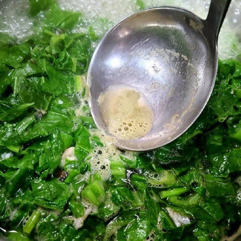 Cho rau cải bẹ xanh vào nồi canh cá rô đang sôi