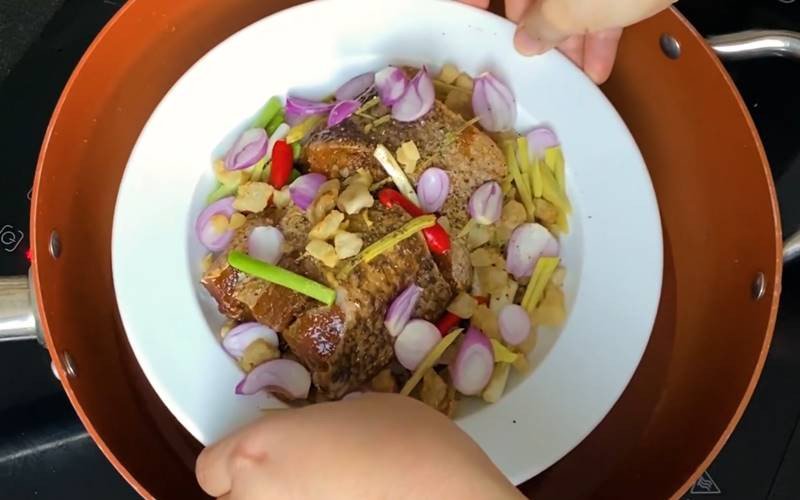 Chưng mắm cá lóc với tóp mỡ và các loại gia vị trên đĩa hấp