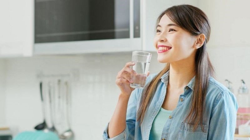 Cốc nước lọc đặt cạnh đĩa bánh bông lan trứng muối, minh họa mẹo uống nước để giảm cảm giác thèm và lượng calo trong bánh bông lan trứng muối